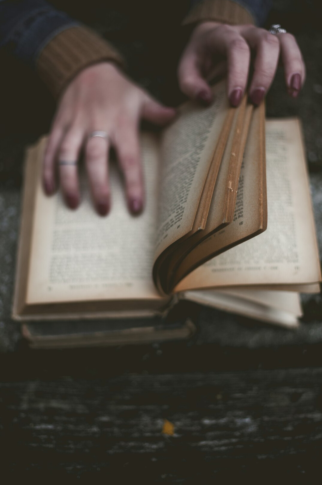 Hands turning pages of an old book with a magnifying glass